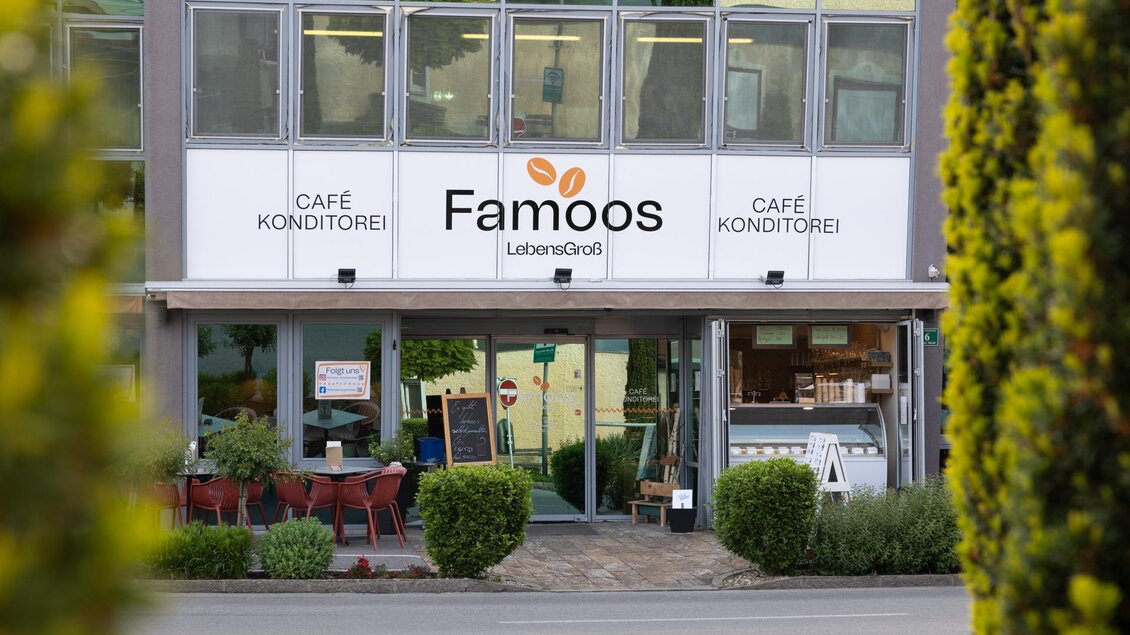 Eingangsbereich der Café-Konditorei Famoos mit Gastgarten und Schaufenstern in Mooskirchen.  | © LebensGroß GmbH