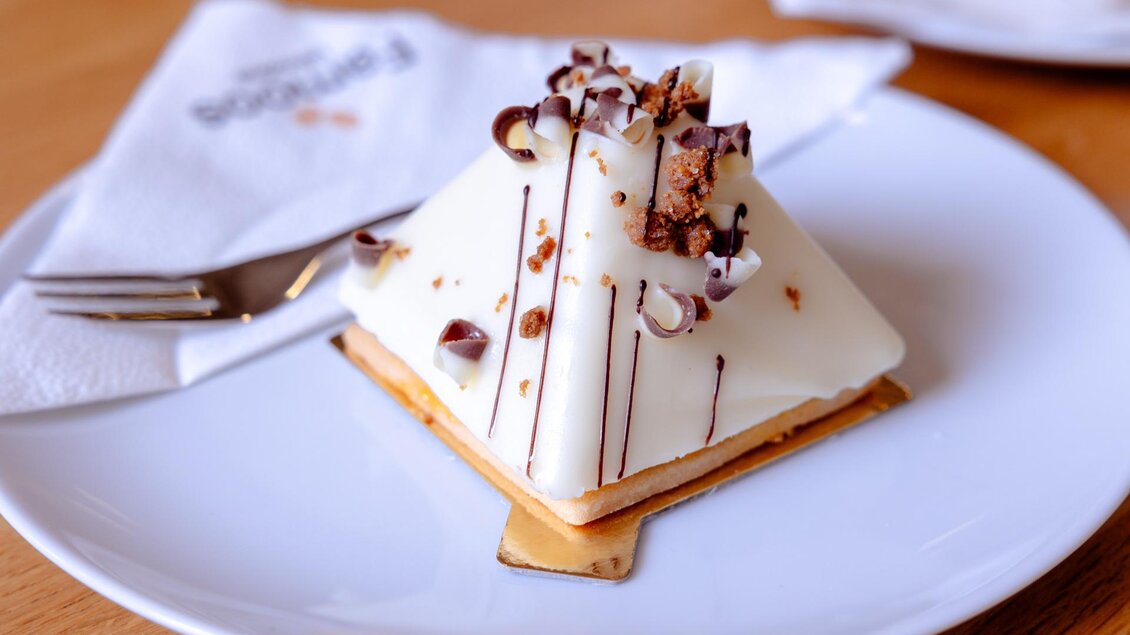 Dessert mit weißer Glasur und Schokodekor auf Teller in der Café-Konditorei Famoos in Mooskirchen.  | © LebensGroß GmbH