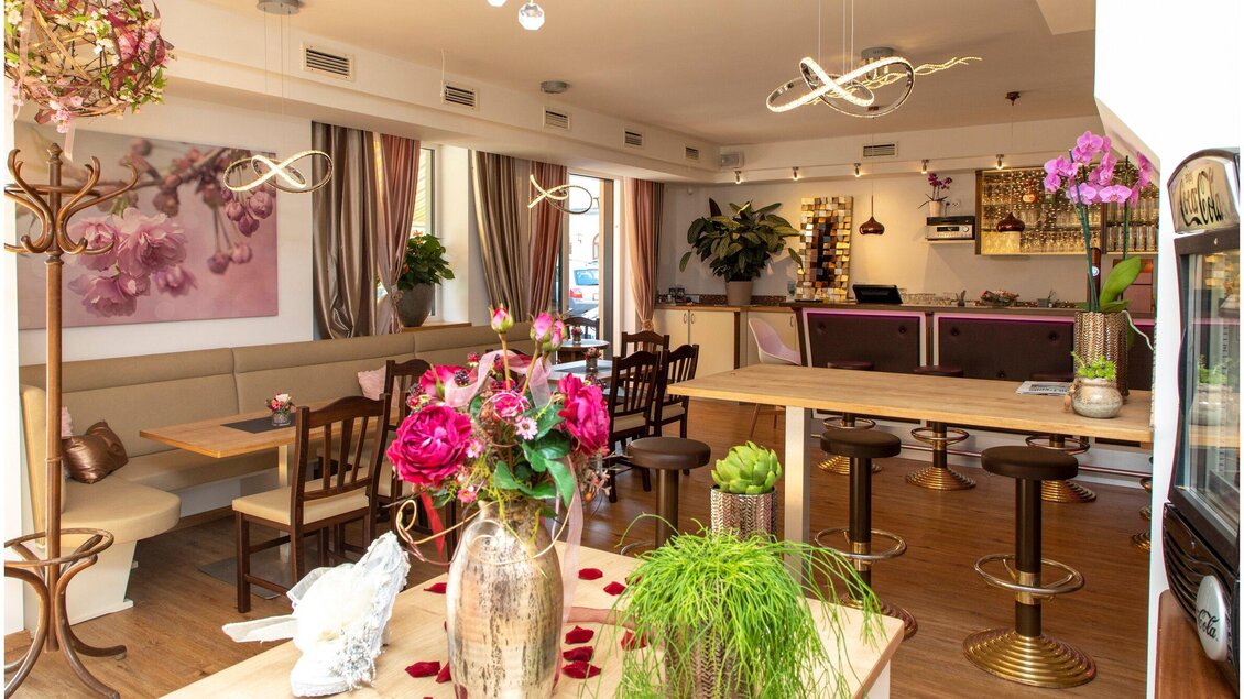 Ein modern eingerichtetes Café mit blühenden Pflanzen und schönen Blumenarrangements. Die warmen Farben und gemütlichen Tische schaffen eine einladende Atmosphäre. | © TV Region Graz - J. Lunghammer