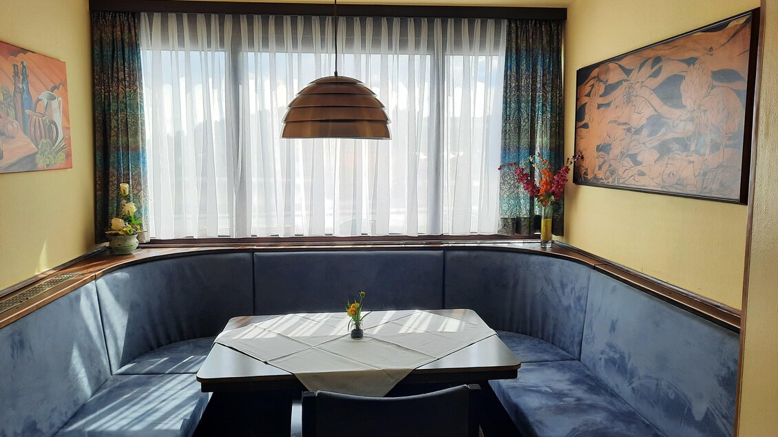Runde Sitzecke im Restaurant Lorber in Köflach mit gepolsterter Bank, Tisch mit Tischdecke, Fensterfront und Hängelampe. | © Restaurant Lorber