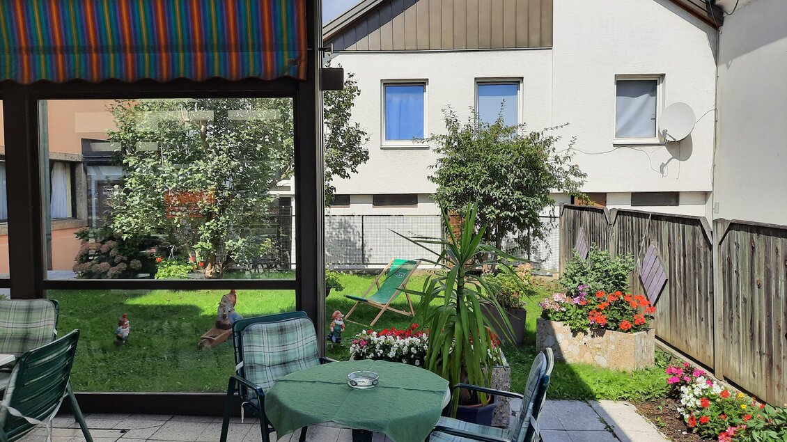 Gastgarten des Restaurants Lorber in Köflach mit Sitzplätzen, Sonnenschutz, Terrasse, Gartenbereich und Wohnhaus im Hintergrund. | © Restaurant Lorber
