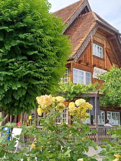 Ein charmantes Holzhaus umgeben von üppigem Grün. Im Vordergrund blühen gelbe Rosen. | © TV Südsteiermark - Löschnig Irene