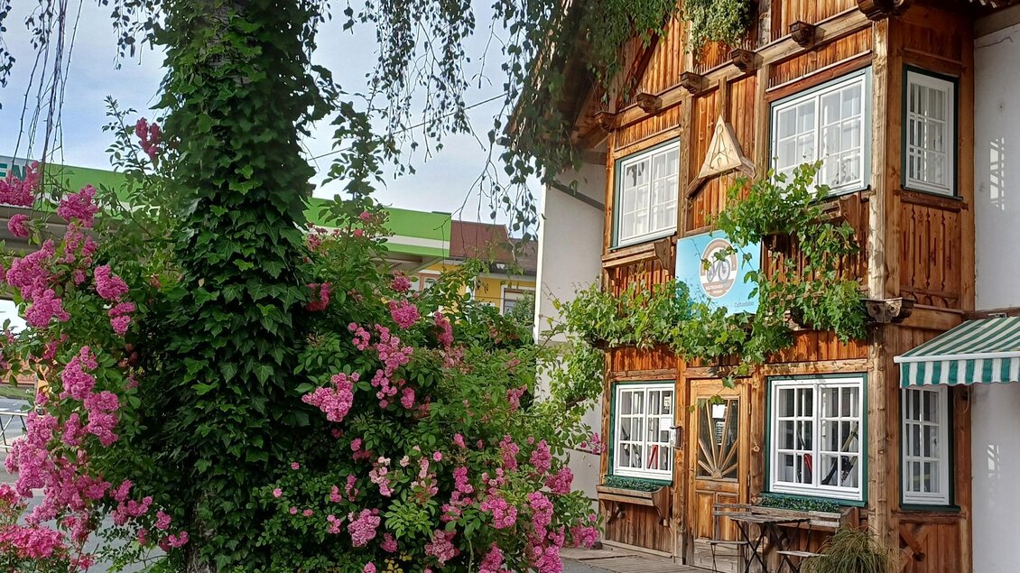 Ein charmantes Holzhaus mit bunten Blumen und grünem Laub. Die Fenster sind reich verziert, und es herrscht eine einladende Atmosphäre. | © TV Südsteiermark - Löschnig Irene