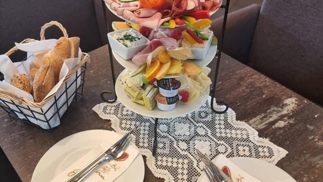 Ein stilvolles Arrangement mit frischem Obst, Gemüse und Aufschnitt auf einem Etagere. Dazu zwei Teller und Besteck auf einem Tisch gedeckt. | © Cafe GAnde