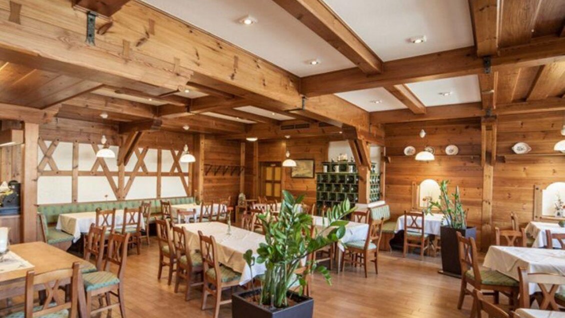 Ein gemütliches Restaurant mit Holzwänden und Holzdekor. Tische und Stühle sind ordentlich angeordnet, und Pflanzen bringen frisches Grün in den Raum. | © GH Kirchenwirt Wies