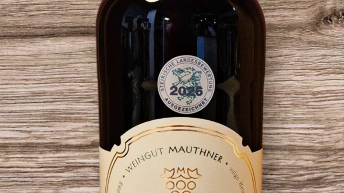 Eine Flasche Schilcher Traubensaft mit einem eleganten Etikett. Der Saft ist klar und befindet sich vor einer holzartigen Hintergrundoberfläche.