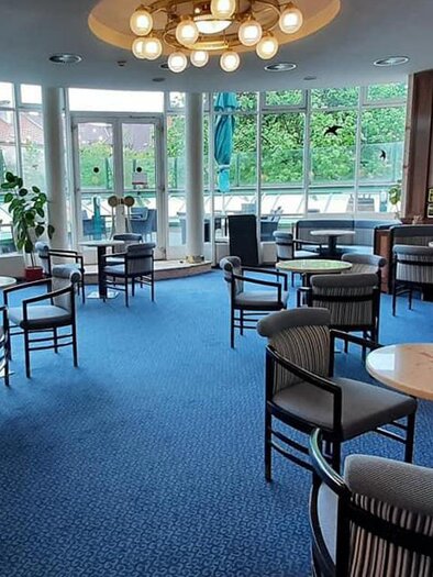 Ein modernes Café mit gemütlichen Sitzbereichen und einem großen Fenster, das viel Licht hereinlässt. Der Raum ist stilvoll eingerichtet und lädt zum Verweilen ein. | © Mitt'n drin