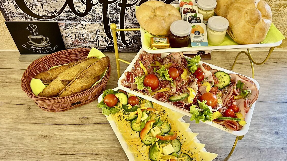 Ein Teller mit frischem Salat, Tomaten und verschiedenen Beilagen. Dazu gibt es Brötchen und eine Auswahl an Marmelade. | © Márta Martin