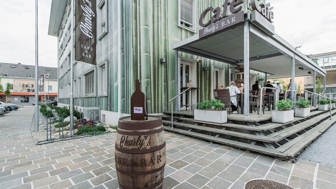 Außenansicht von Charly’s Café & Bar in Köflach mit Terrasse, Eingangsbereich und Fassadenbeschriftung in der Steiermark. | © Die Abbilderei