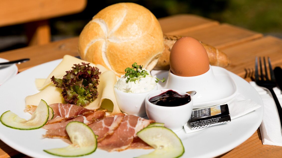 Ein Teller mit frischem Brötchen, Schinken, Käse und einem weichgekochten Ei. Dazu gibt es Salat, Gurkenscheiben und eine kleine Schale mit Marmelade. | © Region Graz - Harry Schiffer