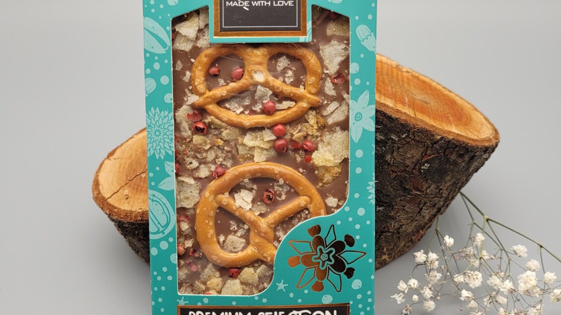 Eine ansprechende Verpackung mit handgemachten Snacks, die Brezeln und Nüsse enthalten. Die Verpackung hebt die Premiumqualität und die Herkunft aus Österreich hervor.