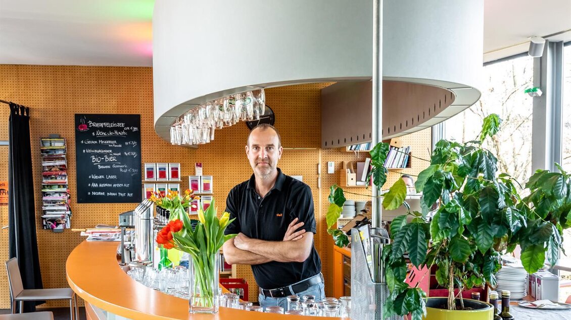 Ein moderner Barbereich mit einem freundlichen Barkeeper. Bunte Lichter und Pflanzen schaffen eine einladende Atmosphäre. | © Stephan Friesinger