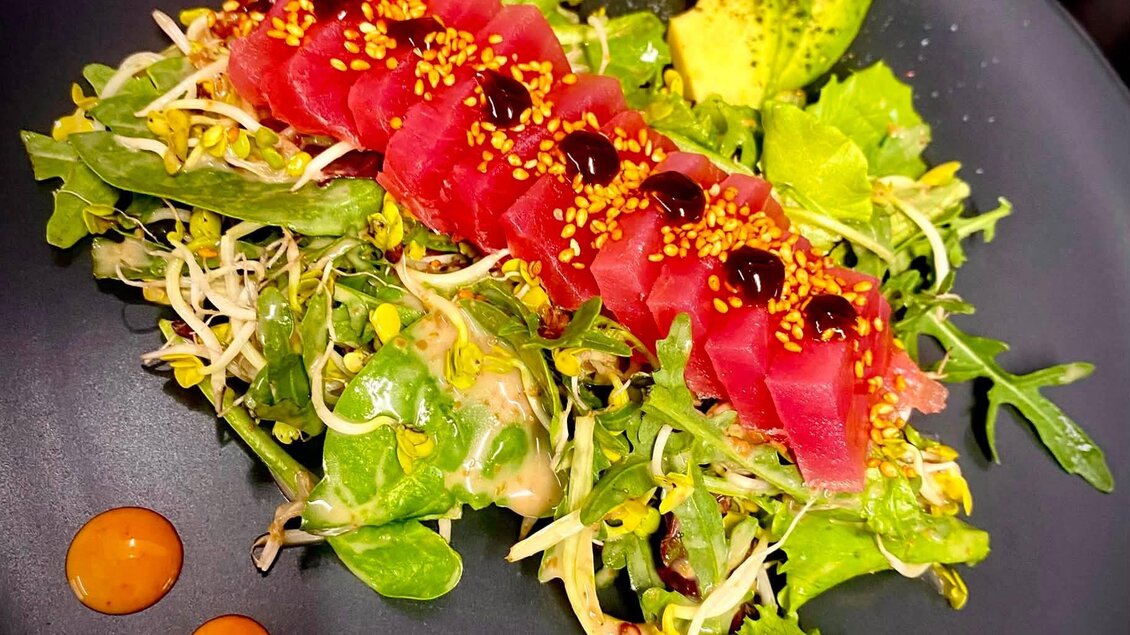 Ein elegantes Gericht mit frischem Salat, Thunfisch und Avocado. Die Präsentation ist ansprechend mit einer Garnitur aus Sesam und Saucenpunkten. | © Sabine Marschnig