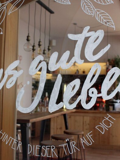 <p>Ein einladendes Café und Restaurant mit Holzinterieur. Auf der Glasscheibe der Tür steht der Schriftzug "Das gute Leben".</p> | © TVB Ausseerland Salzkammergut