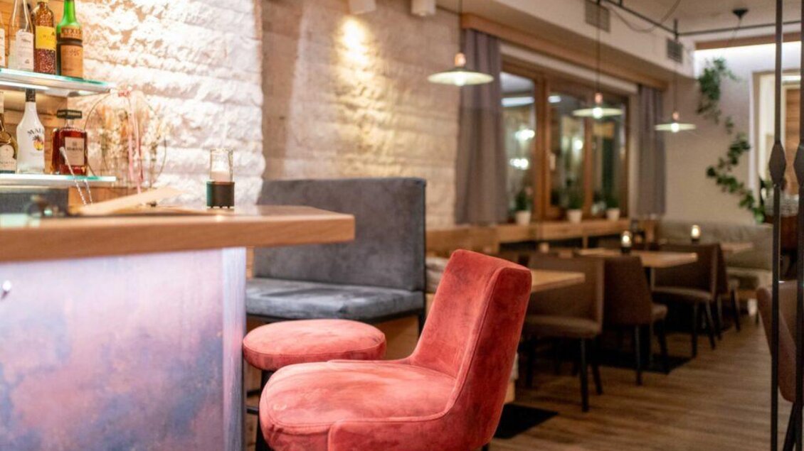 Eine einladende Bar mit stilvollen Sitzgelegenheiten in sanften Farben. Der Raum ist hell und modern gestaltet, ideal für gesellige Abende. | © Maurer