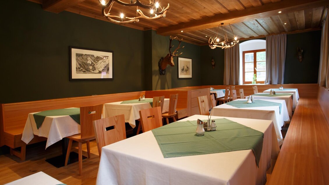 Ein gemütliches Restaurant mit Holztischen und -stühlen. Die Tische sind mit weißen Tischdecken und grünen Platzsets dekoriert. | © ZWHS