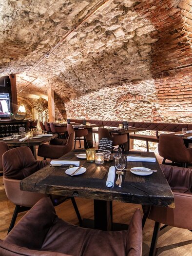 Ein stilvolles Restaurant mit gemütlichen, braunen Stühlen und einem rustikalen Backsteinarchitektur. Der Raum ist gut beleuchtet und bietet eine einladende Atmosphäre. | © Photoworkers