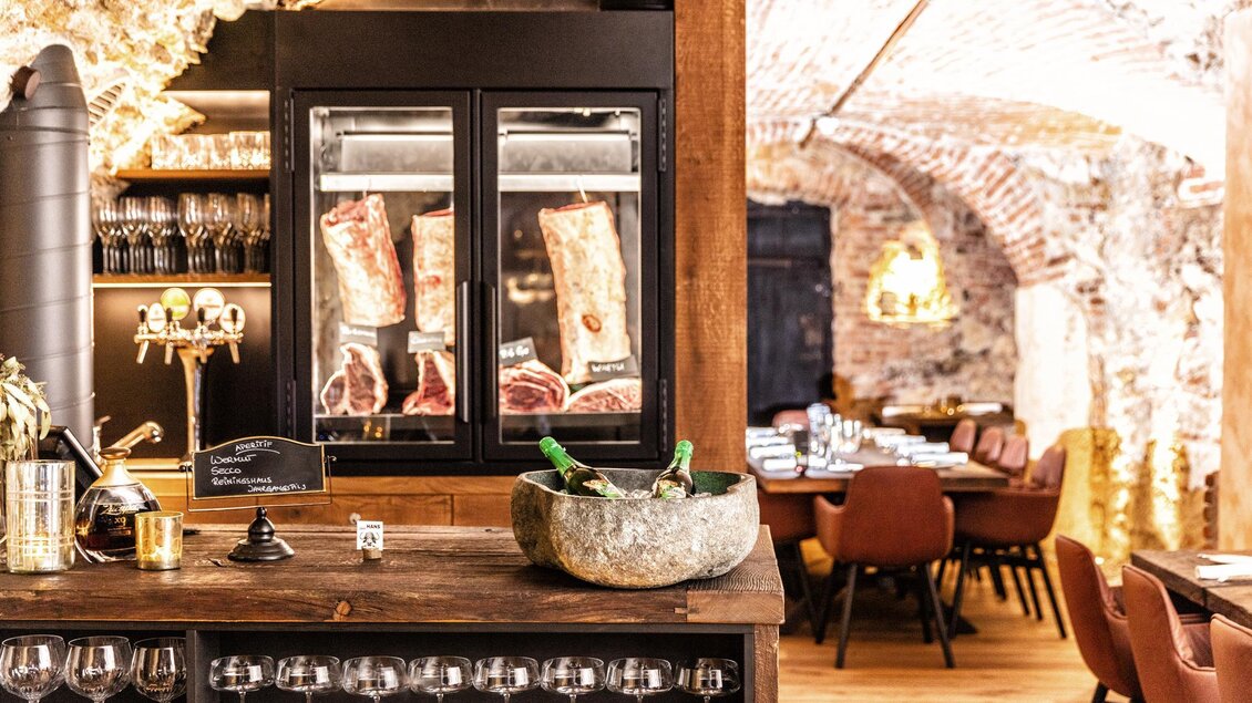 Ein elegantes Restaurant mit einer stilvollen Bar und rustikalen Ziegelwänden. Im Hintergrund sind gemütliche Essplätze zu sehen. | © Photoworkers