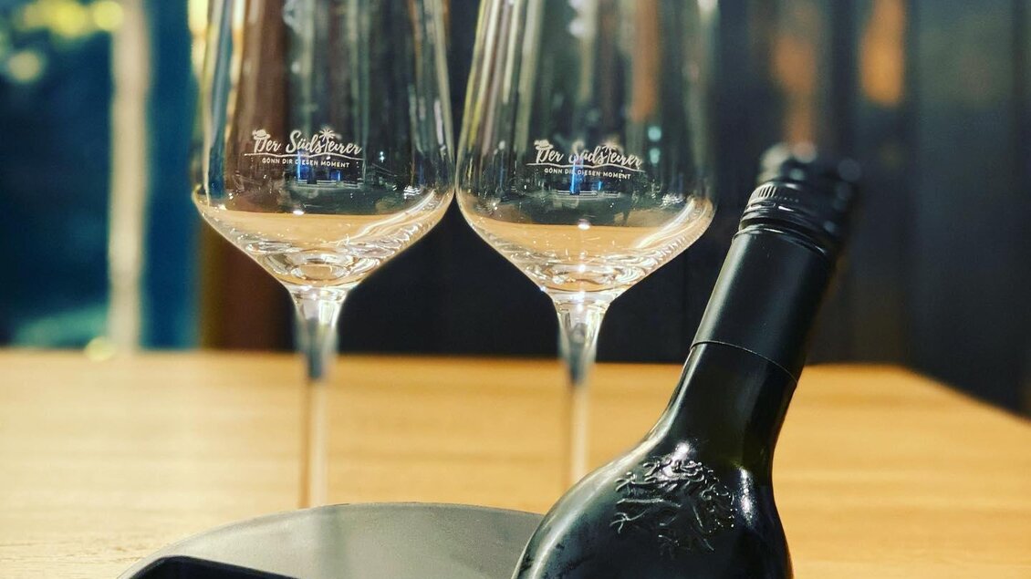 Eine Flasche Wein steht in einem Kühler, daneben stehen zwei Weingläser. Das Setting vermittelt eine elegante und einladende Atmosphäre. | © Der Südsteirer_Warasdin