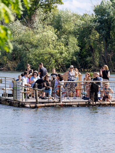 Gruppe bei geführter Flossfahrt auf der Mur, umgeben von Flusslandschaft in Graz. | © Die Flösserei-Harry Schifer