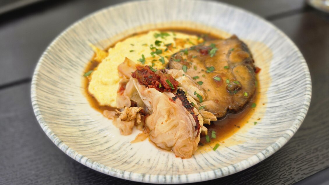 Ein Teller mit zartem Fleisch und einer cremigen Beilage. Darauf sind frische Kräuter und eine aromatische Sauce sichtbar. | © Oststeiermark Tourismus