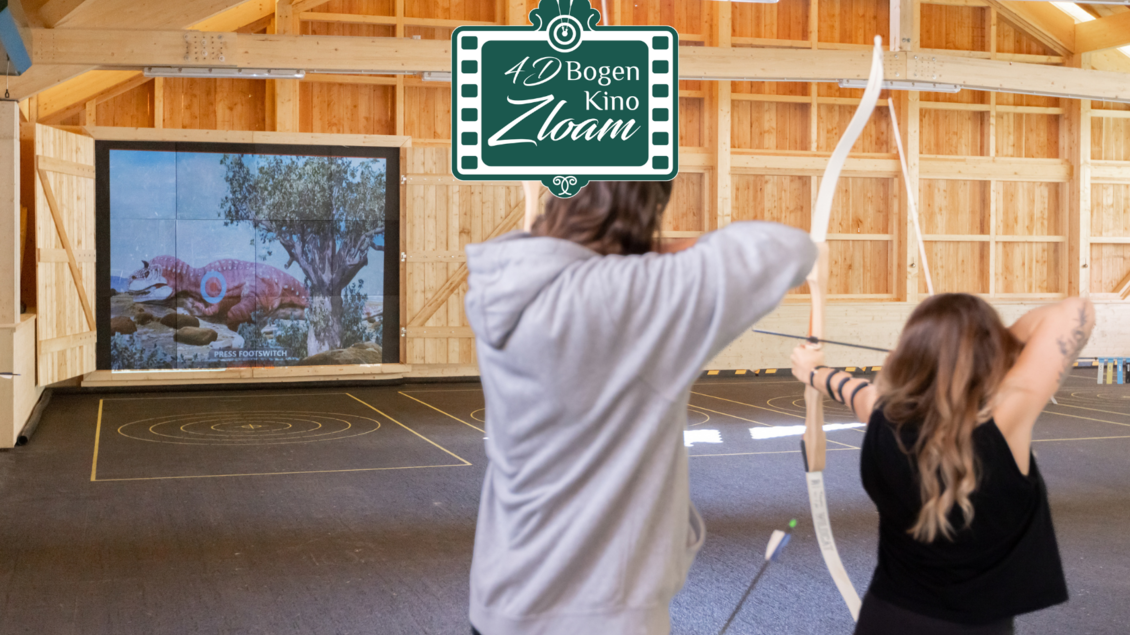 Eine Gruppe von Personen schießt mit Pfeil und Bogen auf eine Leinwand. Im Hintergrund ist ein großes Bild von einem bunten Fisch zu sehen. | © www.zloam.at