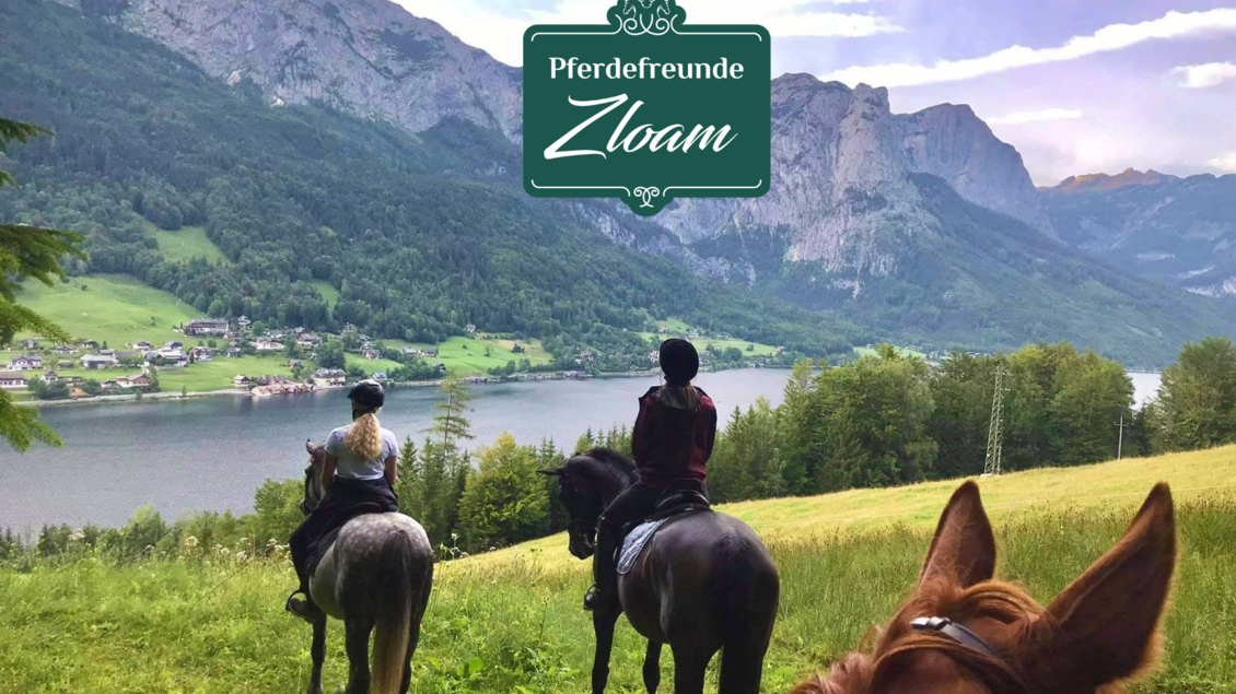Reiterblick auf einen malerischen See umgeben von Bergen. Zwei Personen auf Pferden genießen die Natur. | © www.zloam.at