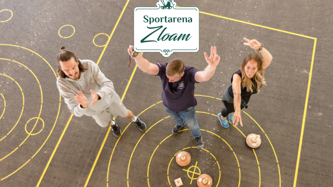 Drei Personen spielen ein Spiel in der Sportarena Zloam und zeigen ihre Freude. Auf dem Boden sind Zielkreise und Spielobjekte sichtbar. | © www.zloam.at