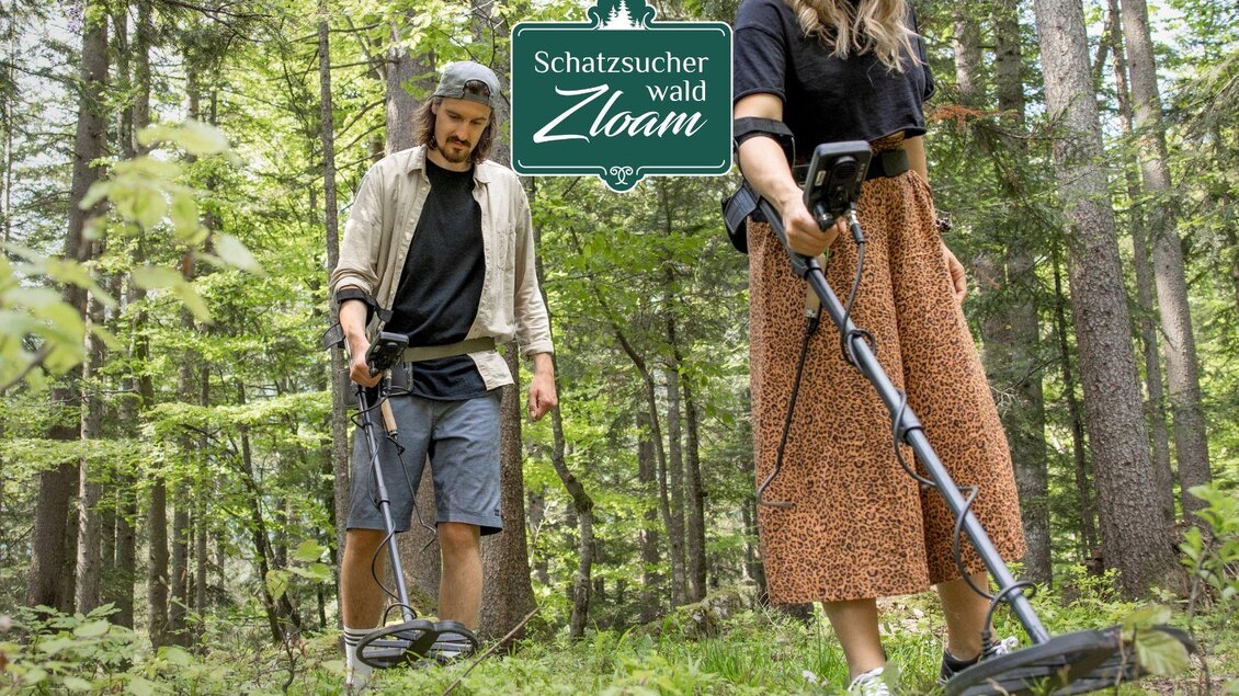 Zwei Personen suchen mit Metalldetektoren im Wald. Umgeben von Bäumen und Grün entdecken sie verborgene Schätze. | © www.zloam.at