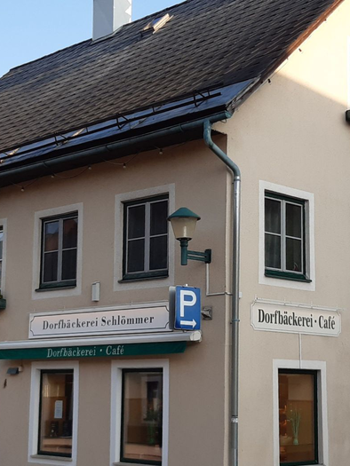 <p>Die Bäckerei und Cafe Schlömmer befindet sich in einem hellen Mehrfamilienhaus in Bad Mitterndorf mit Blumen an den Fenstern.  | © Daniela Casari