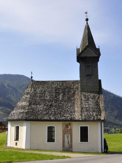Eine kleine, charmante Kirche mit einem hohen Turm. Sie liegt malerisch in einer grünen Landschaft vor den Bergen. | © TVB Ausseerland - Salzkammergut/Franz Steinegger