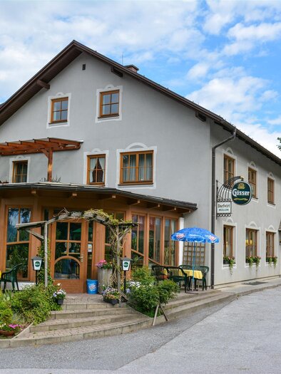 Außenansicht des Gasthauses Dorfwirt Müller in Bärnbach, mit einladendem Eingangsbereich, Blumen und Außensitzplätze. | © Dorfwirt Müller
