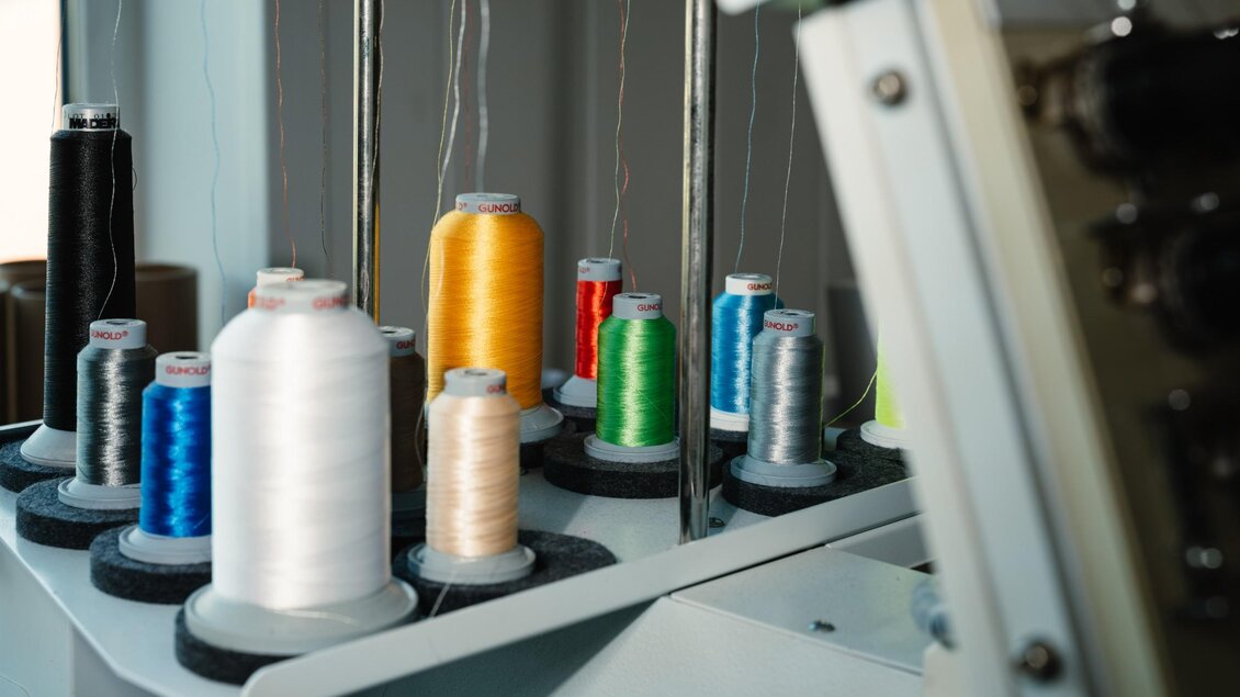 Garnrollen in verschiedenen Farben an einer Stickmaschine im Druckhaus Moser. | © Bernd Grosseck