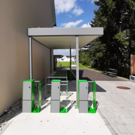 Eine moderne Fahrradstation mit mehreren Abstellplätzen unter einem Vordach. Im Hintergrund sind Bäume und ein Gehweg sichtbar. | © Stadtgemeinde Fehring