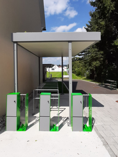 Eine moderne Fahrradstation mit mehreren Abstellplätzen unter einem Vordach. Im Hintergrund sind Bäume und ein Gehweg sichtbar. | © Stadtgemeinde Fehring