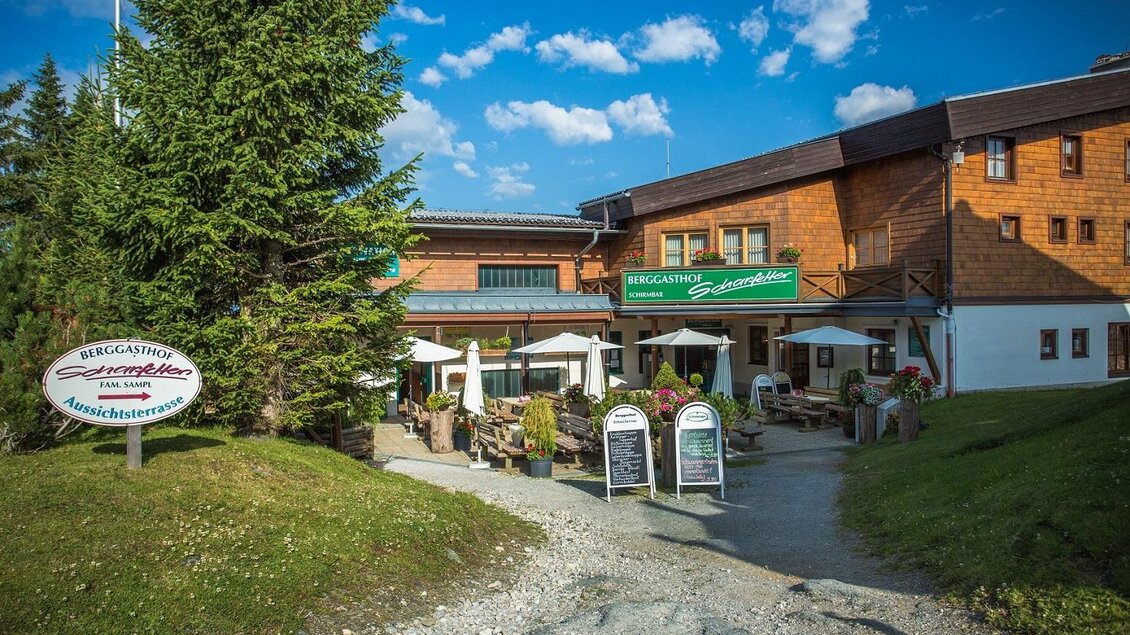 Ein einladendes Gasthaus inmitten der Natur mit einer schönen Terrasse. Umgeben von Bäumen und einem klaren Himmel. | © TVB Haus-Aich-Gössenberg@René Eduard Perhab