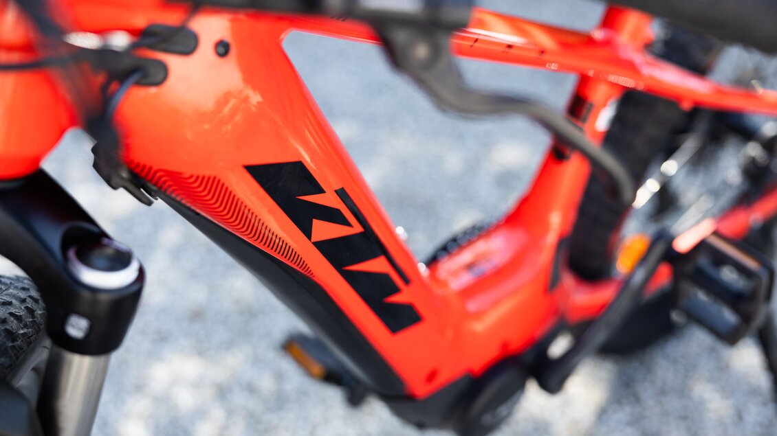 Ein leuchtend rotes Fahrrad mit einem modernen Design und markanter Schriftart. Die Nahaufnahme zeigt den Rahmen und Teile der Ausrüstung. | © Kerstin Godl