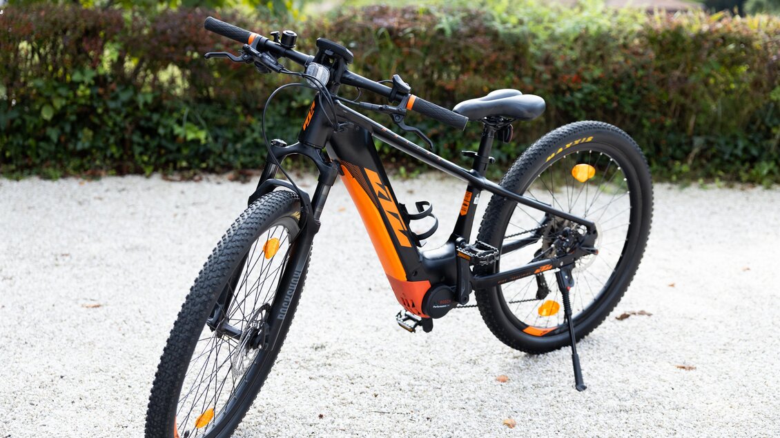 Ein modernes Mountainbike in Schwarz und Orange steht auf einem Kiesboden. Die Reifen sind für unebene Gelände geeignet und das Design ist sportlich. | © Kerstin Godl