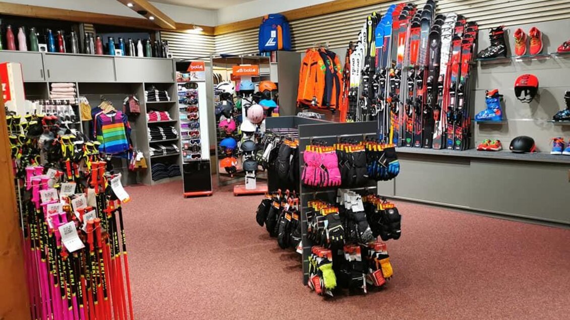 Ein Sportgeschäft mit einer großen Auswahl an Skiausrüstung und Bekleidung. Regale sind mit Ski, Handschuhen und anderen Wintersportartikeln gefüllt. | © Sport Buchebner