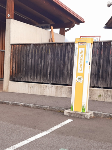 Eine unauffällige Ladestation in einer ruhigen Umgebung. Im Hintergrund ist ein Holzhaus mit Fenstern zu sehen. | © Thermen- & Vulkanland Steiermark