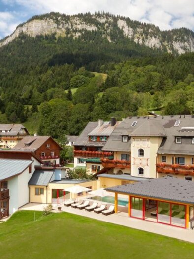 A picturesque hotel in a green landscape, surrounded by mountains. The garden with loungers invites you to relax. | © Hotel DER HECHL
