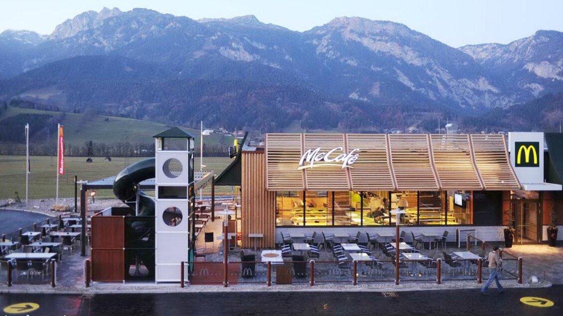 Ein McDonald's Restaurant mit einem McCafé in einer malerischen Berglandschaft. Draußen befinden sich Sitzgelegenheiten und ein Spielplatz. | © Hauser Kaibling