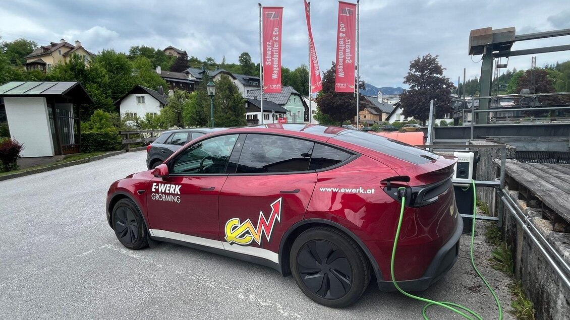 Zu sehen ist eine Elektro-Tankstelle wo gerade ein roter Tesla aufladet. Die Ladestation befindet sich beim E- Werk Schwarz Wagendorffer in Bad Aussee. | © TVB Ausseerland- Salzkammergut_Nathalie Schröttenhamer