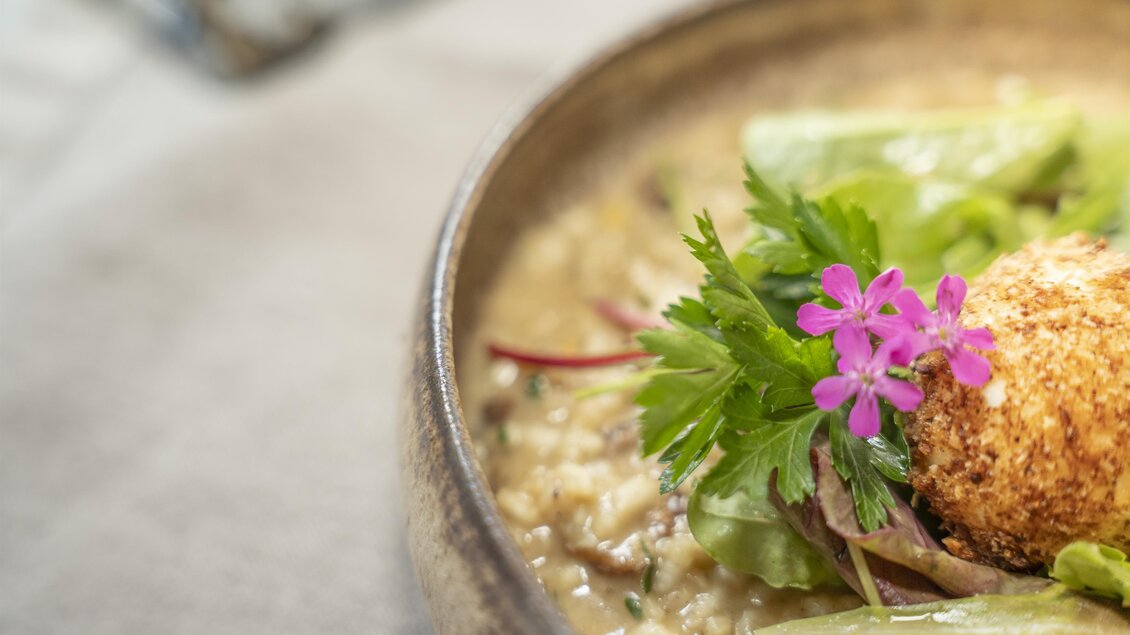 Ein schmackhaftes Gericht in einer dekorativen Schüssel, verziert mit frischen Kräutern und einer Blume. Die Kombination von Aromen und Farben macht das Essen ansprechend.