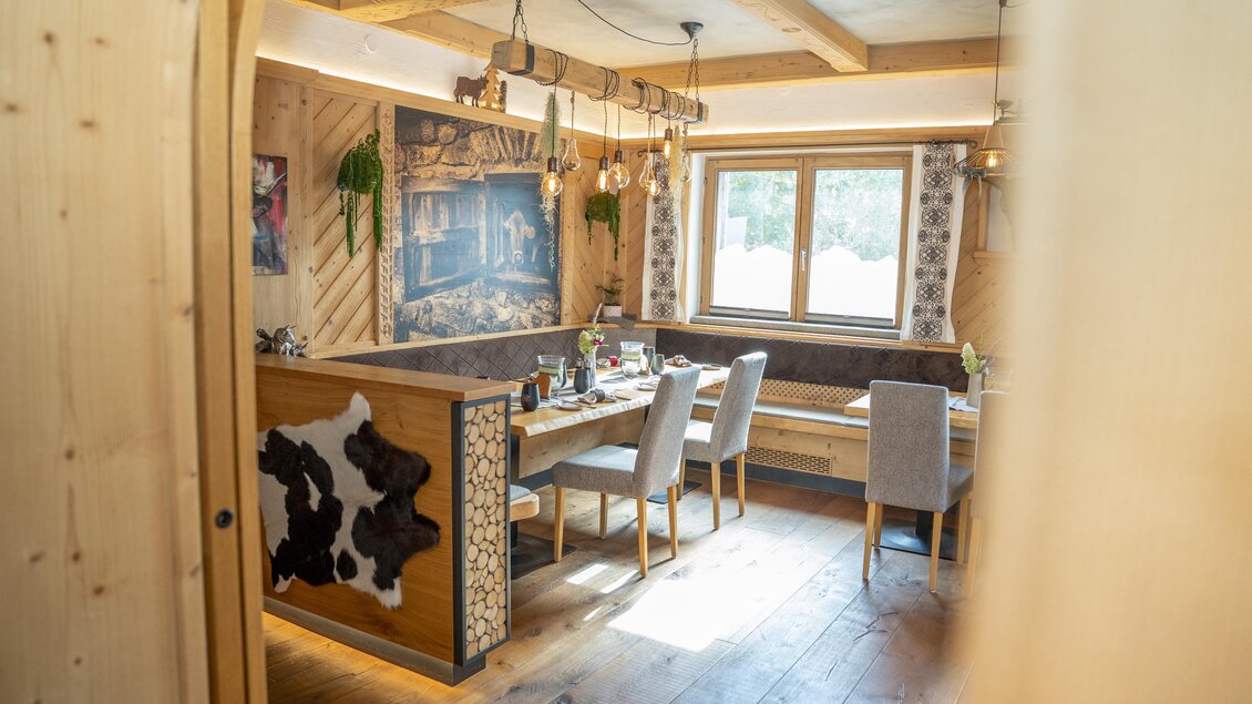 Ein gemütliches Restaurant mit Holzinterieur und einer großen Fensterfront. Der Tisch ist elegant gedeckt und bietet Platz für mehrere Gäste.