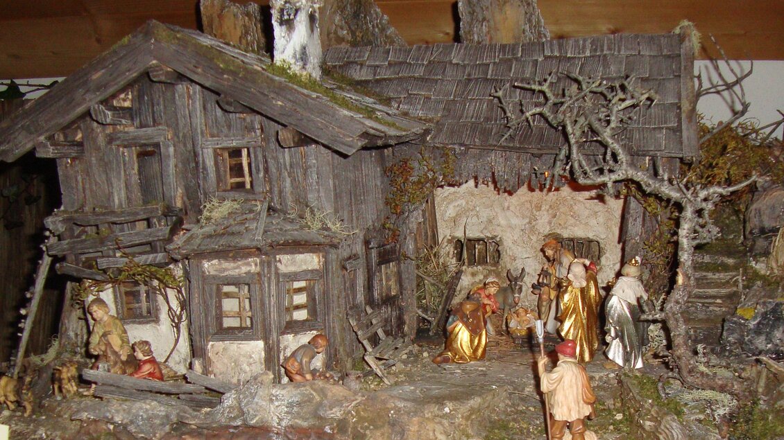 Eine detailreiche Krippe mit einem alten Holzhaus und Figuren, die die biblische Geschichte darstellen. Im Hintergrund sind Bäume und Felsen zu sehen. | © Elisabeth Schupfer