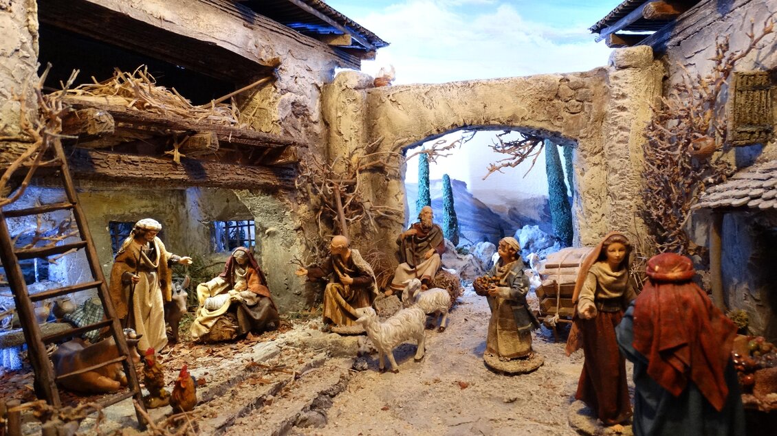 Eine traditionelle Krippe mit Figuren, die eine Szene aus der Weihnachtsgeschichte darstellen. Die Umgebung ist rustikal und zeigt alte Gebäude und natürliche Elemente. | © Elisabeth Schupfer