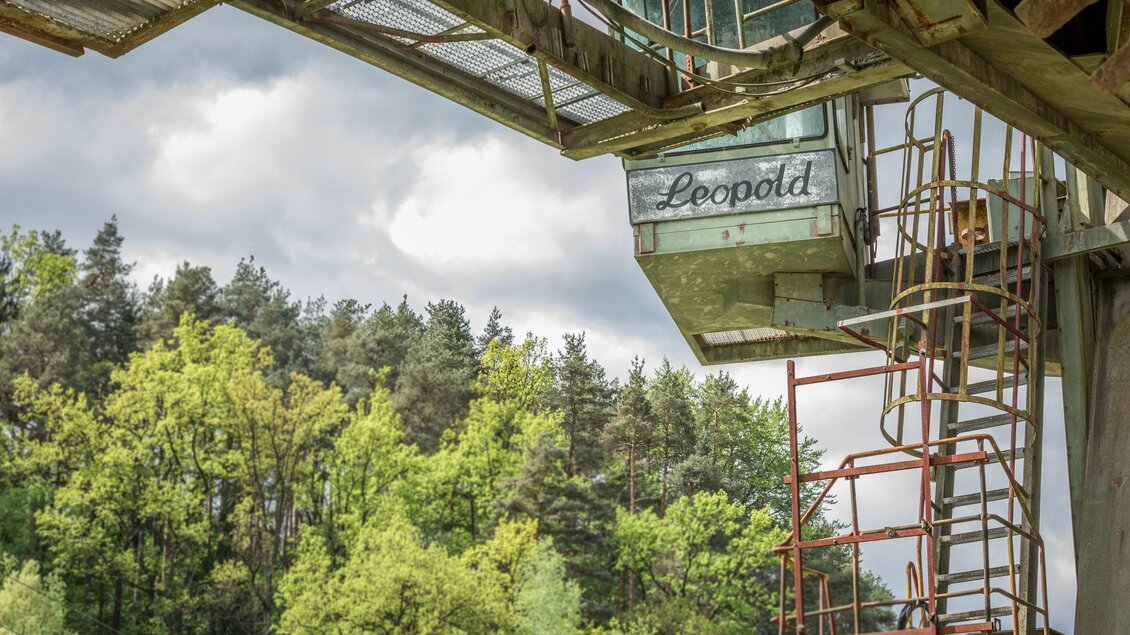 Führerstand des Schaufelradbaggers Leopold mit Namensschriftzug vor grüner Waldkulisse im Zangtal in Voitsberg  | © TV Region Graz - Die Abbilderei