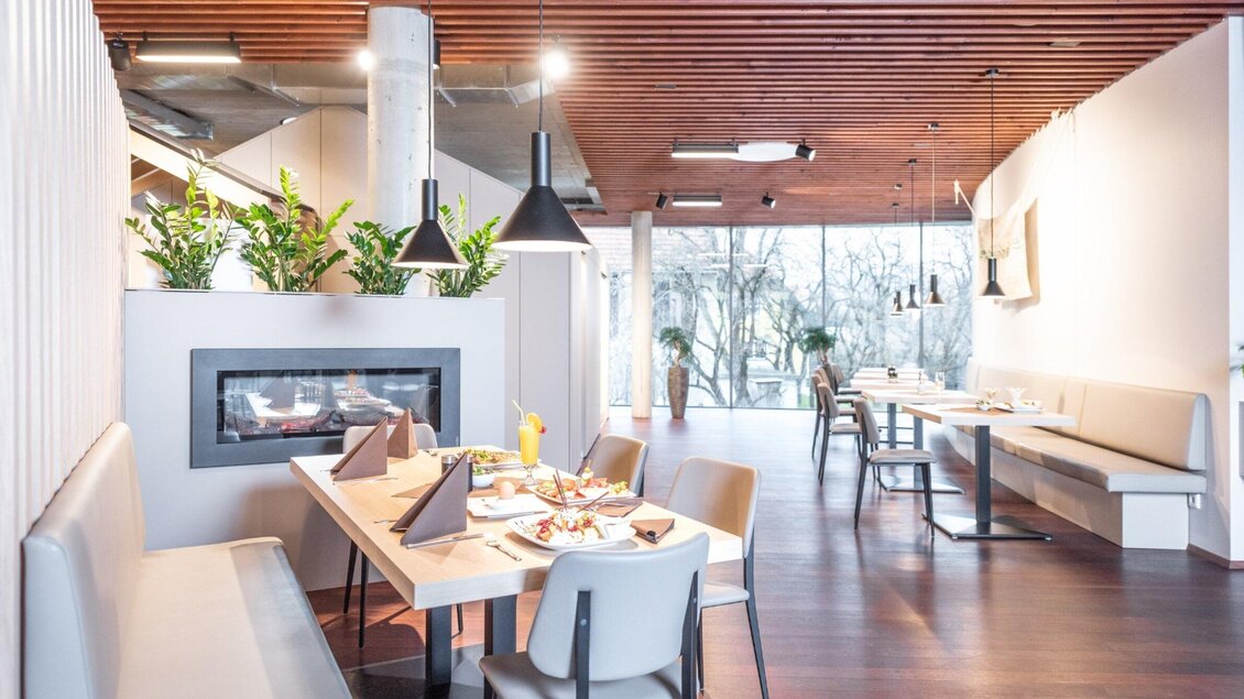 Modernes Restaurant mit Holzelementen, Sitzbänken und Kamin im Energieschiff Mochart in Köflach.  | © Mochart GmbH