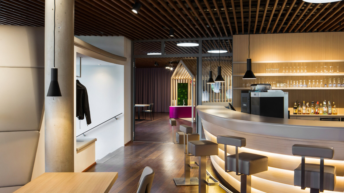 Modern gestalteter Barbereich mit beleuchteter Theke und Sitzplätzen im Energieschiff Mochart in Köflach.  | © Mochart GmbH